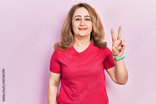 Middle age caucasian woman wearing casual clothes smiling looking to the camera showing fingers doing victory sign. number two.