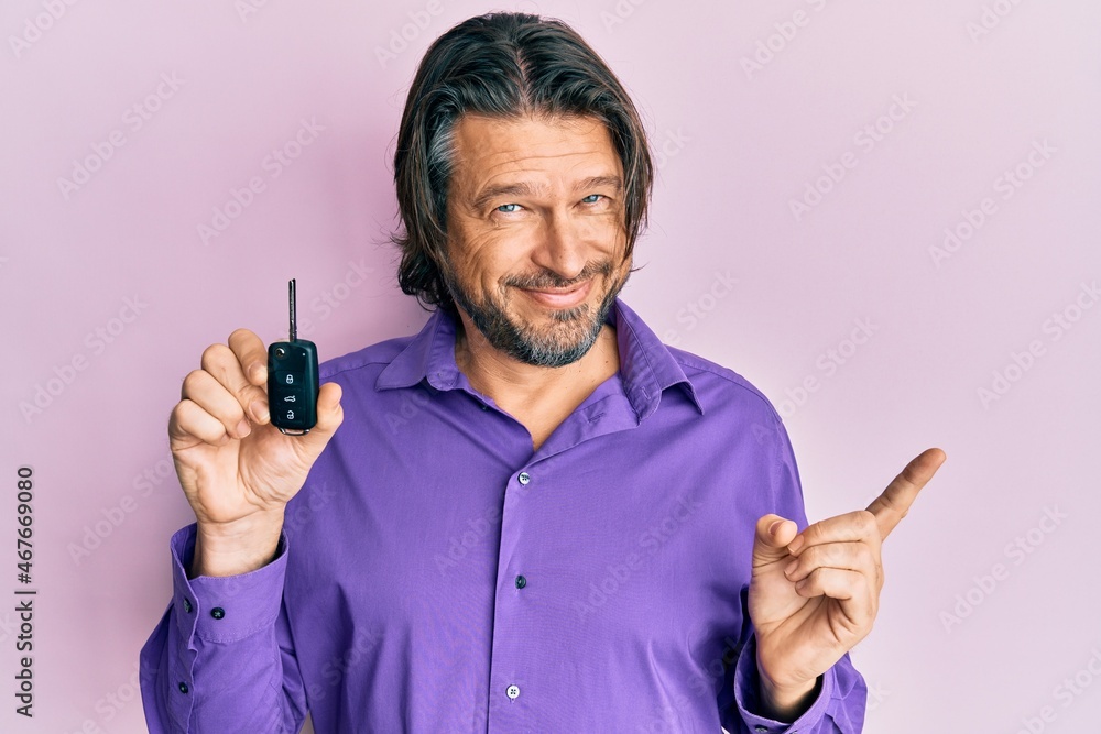 Middle age handsome man holding key of new car smiling happy pointing with hand and finger to the side Middle age handsome man holding key of new car smiling happy pointing with hand and finger to the side