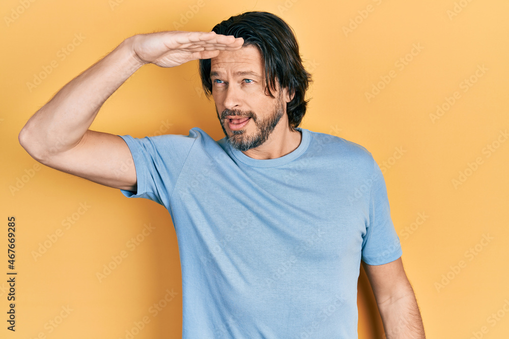 Middle age caucasian man wearing casual clothes very happy and smiling looking far away with hand over head. searching concept. Middle age caucasian man wearing casual clothes very happy and smiling looking far away with hand over head. searching concept.