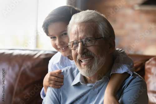 Best grandpa ever. Overjoyed little grandkid cuddle from back smiling mature grandfather in glasses. Loving preteen grandson enjoy kidding playing cute active game having fun together with grandparent