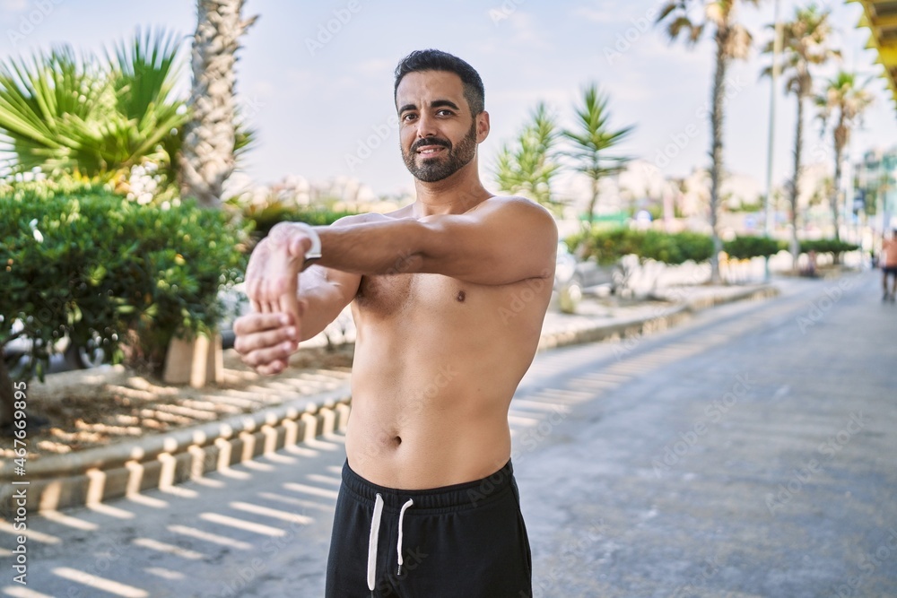 Hispanic man stretching after working out outdoors on a sunny day Hispanic man stretching after working out outdoors on a sunny day