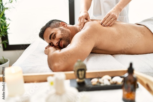 Young hispanic man having back massage at beauty center