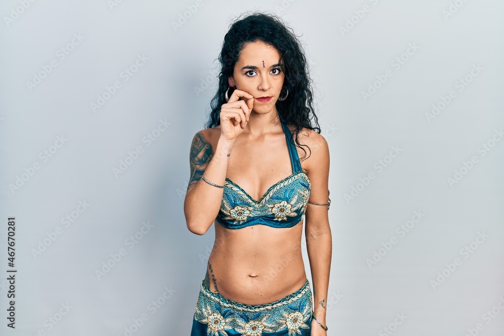 Fototapeta premium Young woman wearing bindi and traditional belly dance clothes mouth and lips shut as zip with fingers. secret and silent, taboo talking