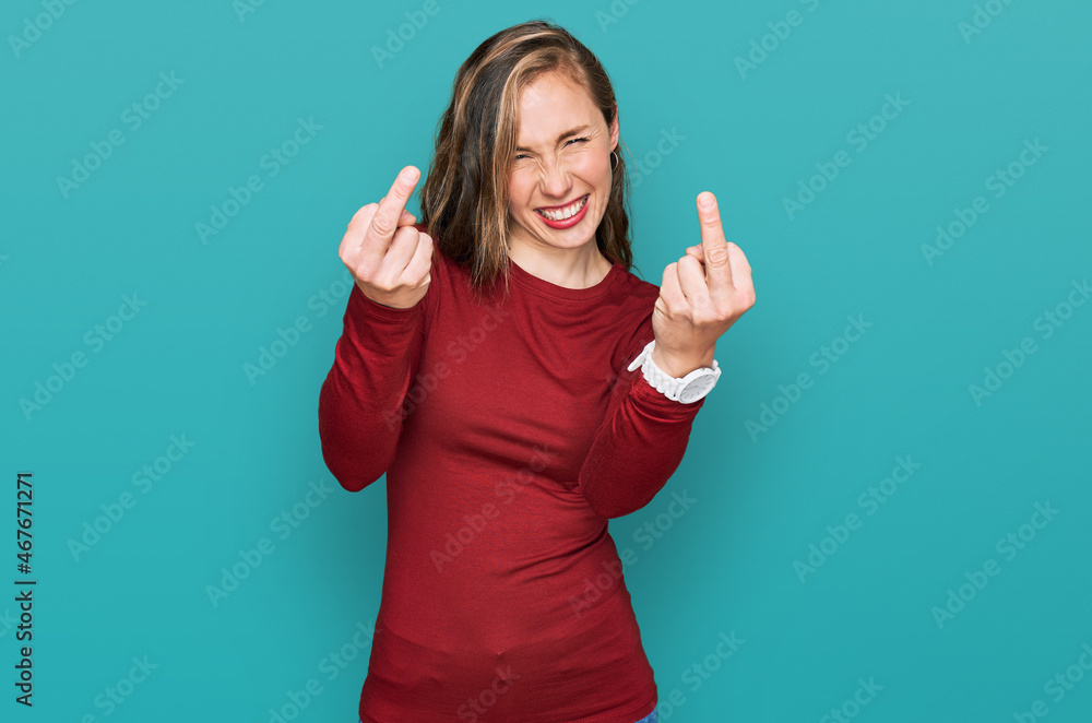 Fototapeta premium Young blonde woman wearing casual clothes showing middle finger doing fuck you bad expression, provocation and rude attitude. screaming excited