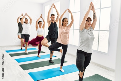 Group of young hispanic people smiling happy training yoga at sport center.