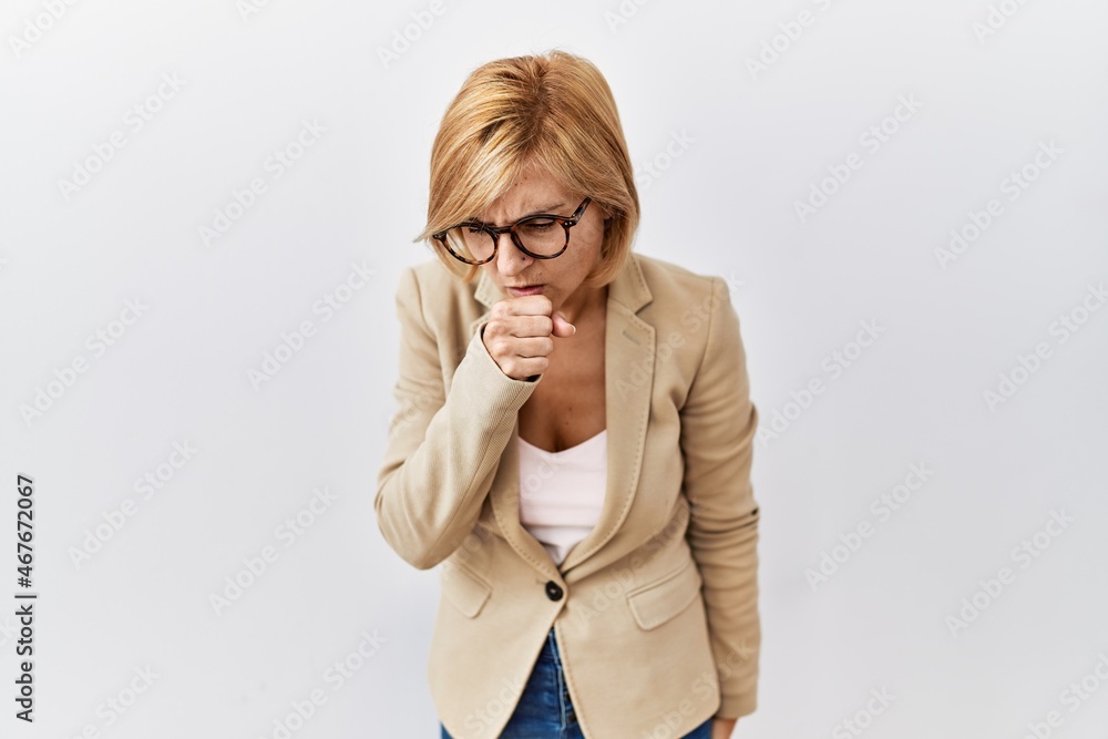 Middle age blonde business woman standing over isolated background feeling unwell and coughing as symptom for cold or bronchitis. health care concept. Middle age blonde business woman standing over isolated background feeling unwell and coughing as symptom for cold or bronchitis. health care concept.