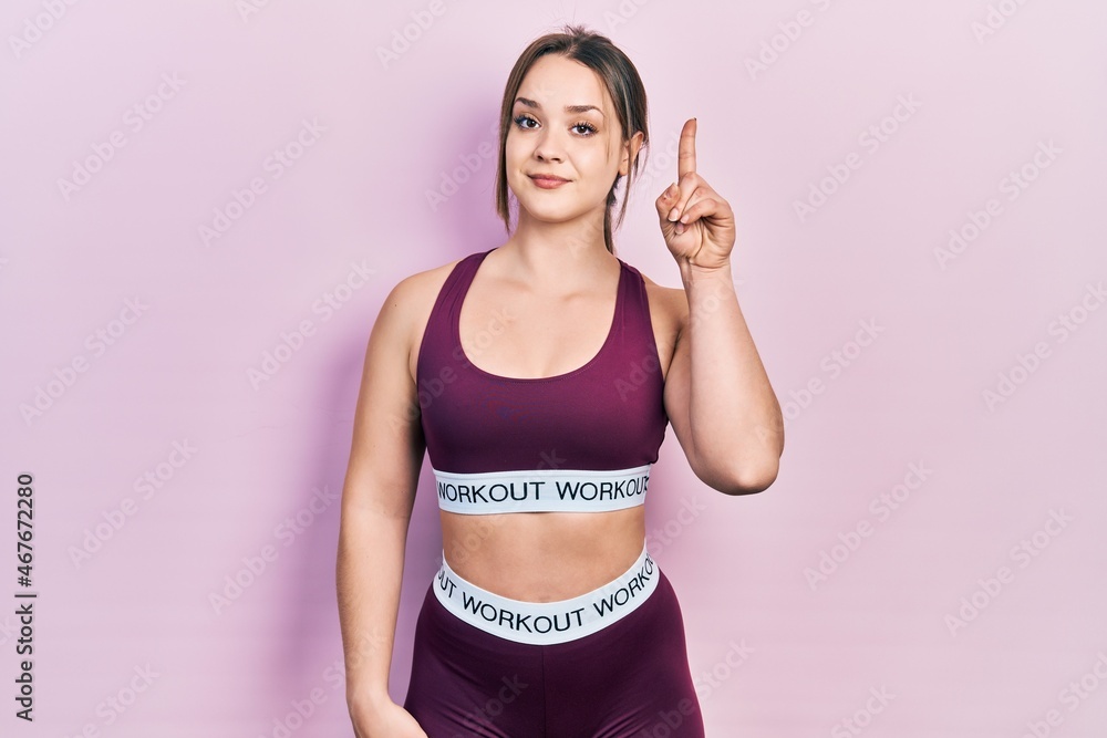 Young hispanic girl wearing sportswear smiling with an idea or question pointing finger up with happy face, number one Young hispanic girl wearing sportswear smiling with an idea or question pointing finger up with happy face, number one