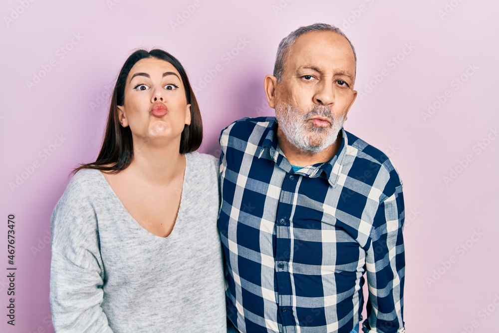 Hispanic father and daughter wearing casual clothes looking at the camera blowing a kiss on air being lovely and sexy. love expression. Hispanic father and daughter wearing casual clothes looking at the camera blowing a kiss on air being lovely and sexy. love expression.