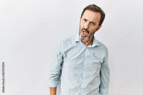 Middle age hispanic man with beard standing over isolated background in shock face, looking skeptical and sarcastic, surprised with open mouth © Krakenimages.com