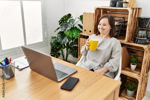 Brunette woman with down syndrome drinking a cup of coffee at business office