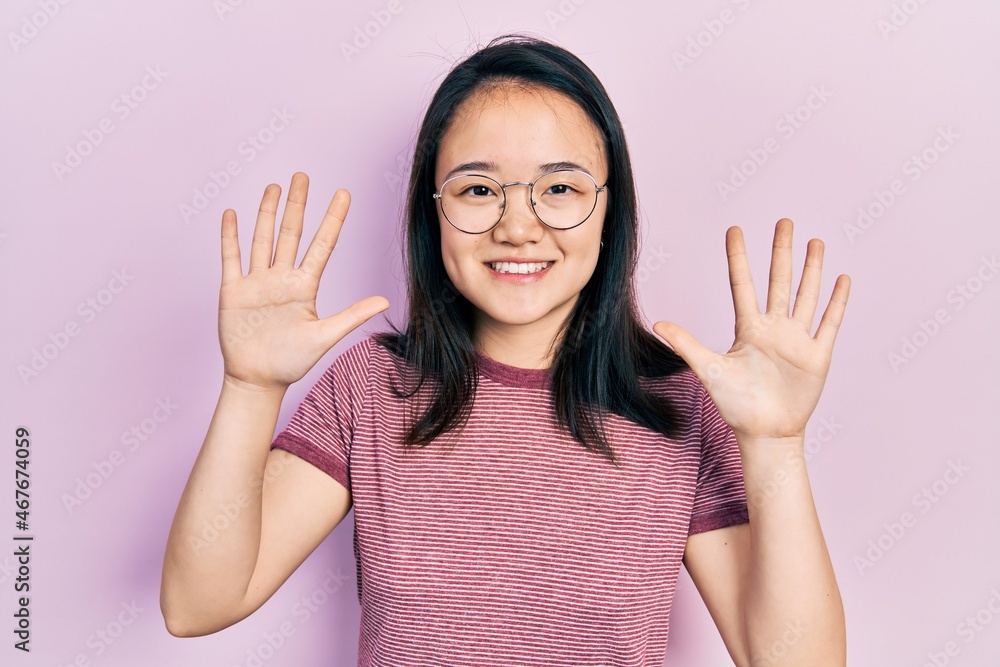 Young chinese girl wearing casual clothes and glasses showing and pointing up with fingers number ten while smiling confident and happy. Young chinese girl wearing casual clothes and glasses showing and pointing up with fingers number ten while smiling confident and happy.