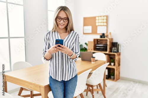 Young chinese woman smiling confident using smartphone at office