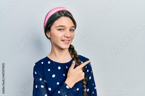 Young brunette girl wearing elegant look cheerful with a smile of face pointing with hand and finger up to the side with happy and natural expression on face