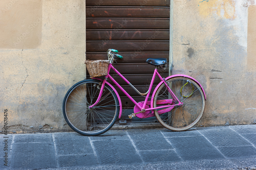 Ladies' bicycle pink, retro with a basket stands against wall