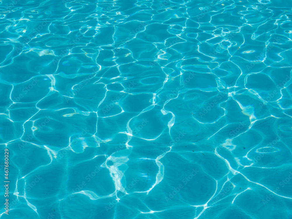 Background of blue transparent pool water with sun glare.