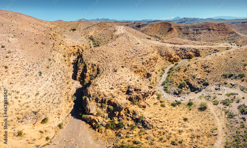 Aerial view of dry canyon in the desert terrain with red rocks in a natural national park. Hiking and recreation area