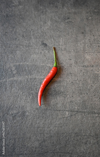 Red hot pepper lies on the letter on the dark gray kitchen countertop. Preparation for cooking. Still life of objects. 