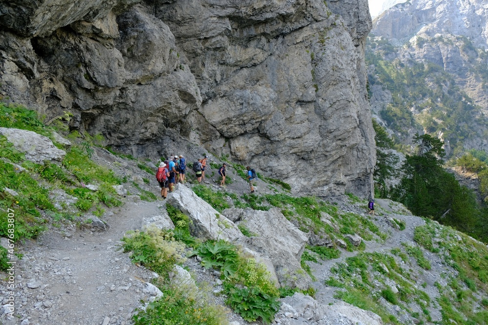 Beautiful mountain views on trail from Theth Valley to Valbona Valley in Albanian Alps. Sihouettes of tourists on path. It is one of the most beautiful high mountain trails.