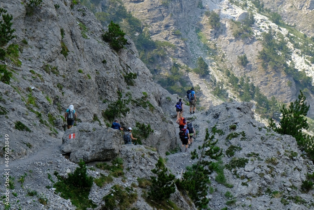 Beautiful mountain views on trail from Theth Valley to Valbona Valley in Albanian Alps. Sihouettes of tourists on path. It is one of the most beautiful high mountain trails.