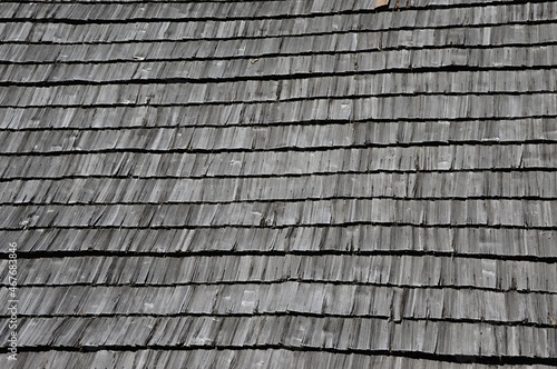 Wooden vintage shingle roof texture, sunlit by summer daylight sunshine. 