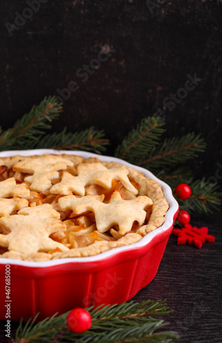 Apple pie with christmas decoration  cookies in the shape of herringbones  on a dark background  copy space.
