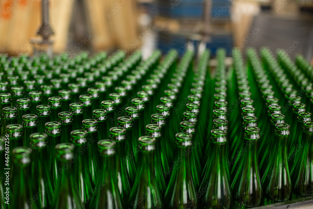 Obraz premium Glass factory, industrial production of glass containers. A lot of empty glass bottles as a background of green glass containers with copy space. Bottles for drinks. Technological work at the factory.