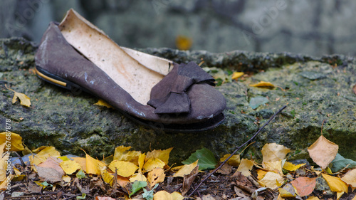 Old torn, but previously stylish women's shoes. worn out shoes. summer shoes with a bow. thrown in the street, in the autumn leaves. the concept of poverty, there is nothing to put on. close-up