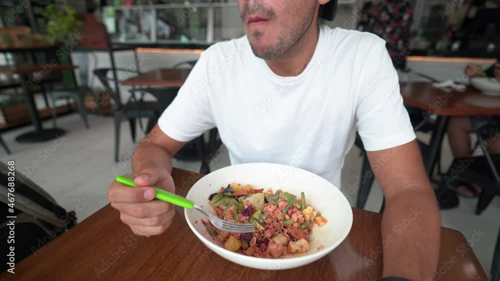 young hispanic man with cap eats salad in a restaurant young hispanic man with cap eats salad in a restaurant