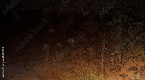 black and gold texture of frost patterns on the window at night
