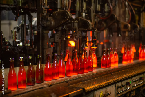 Glass factory  industrial production of glass containers. Modern technology  robots machines make products.Party bottles for drinks. Technological work at the plant. Working atmosphere with copy space