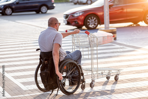 Person with a physical disability pushing cart in front of himself at supermarket parking © romaset