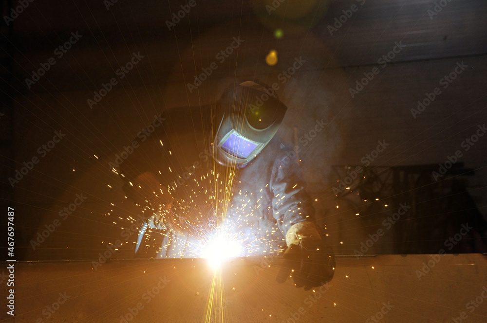 Electric welder at work. A worker welds metal structures at a factory. Flare.
