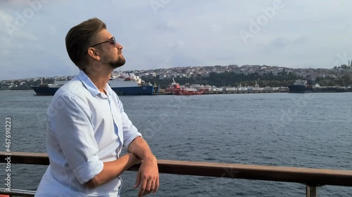 A man in sunglasses rides a boat on the sea and looks at the water.
