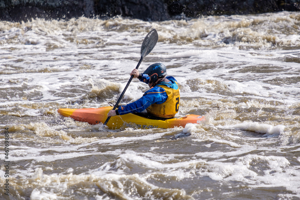 a man in a helmet and a diving suit paddles on a kayak on the waves of a mountain river. mountain dangerous river. overcoming difficulties