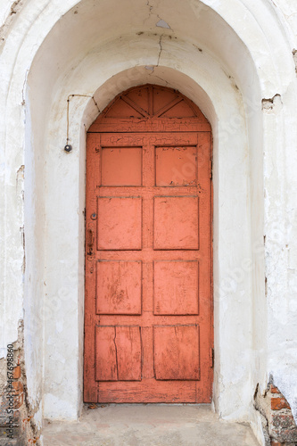 a red semicircular door in an old house, there are traces of destruction on the walls © metelevan
