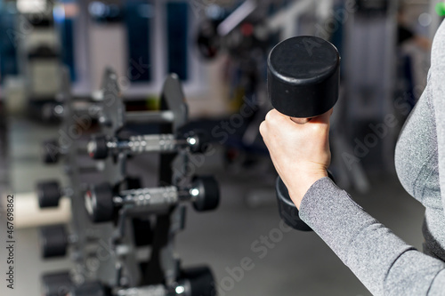 the girl is holding a dumbbell, the background is blurred