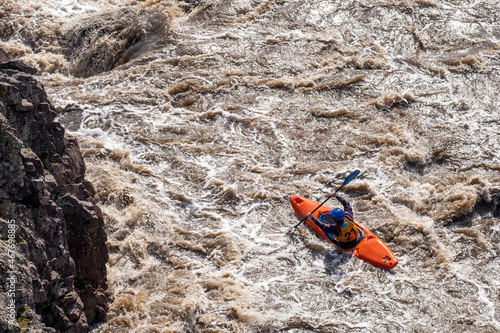 top view of a kayak with a man who overcomes the rapids of the river near the cliff. rock and water