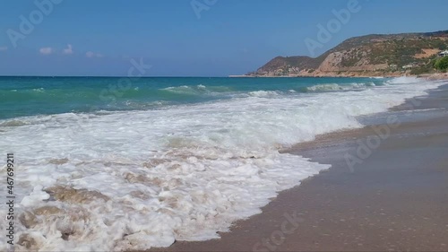 Big sea waves on a sandy beach on a sunny day.