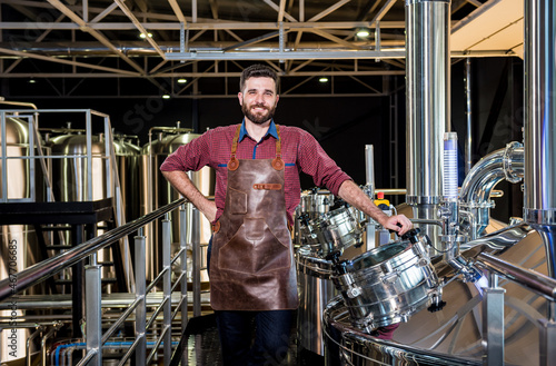 Tableau sur toile Young male brewer in leather apron supervising the process of beer fermentation