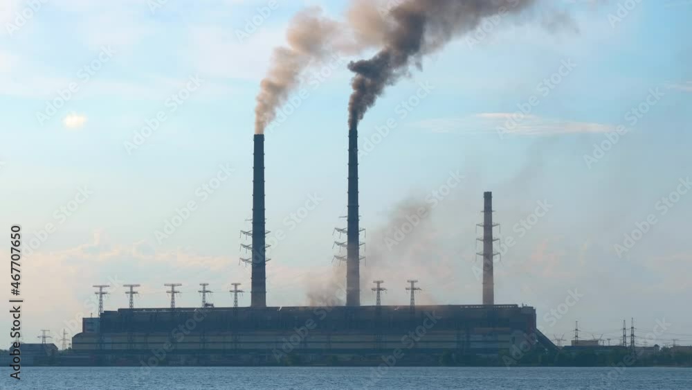 Closeup of thermal power plant high pipes with black smoke moving upwards polluting atmosphere. Production of electrical energy with fossil fuel concept Closeup of thermal power plant high pipes with black smoke moving upwards polluting atmosphere. Production of electrical energy with fossil fuel concept