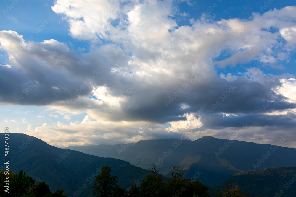 Cumulus clouds over the mountains in the early summer morning. Deterioration of the weather concept