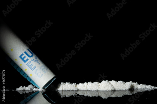 Man hands rolls banknote for using cocaine powder lines. Drug addiction concept. A line of coke on black background. Concept of addiction. Mephedrone, amphetamine, heroin. Serious addiction photo