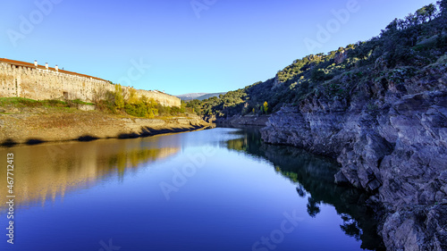 Lozoya river next to the medieval wall and reflection in the water on an autumnal day. Buitrago, Madrid.