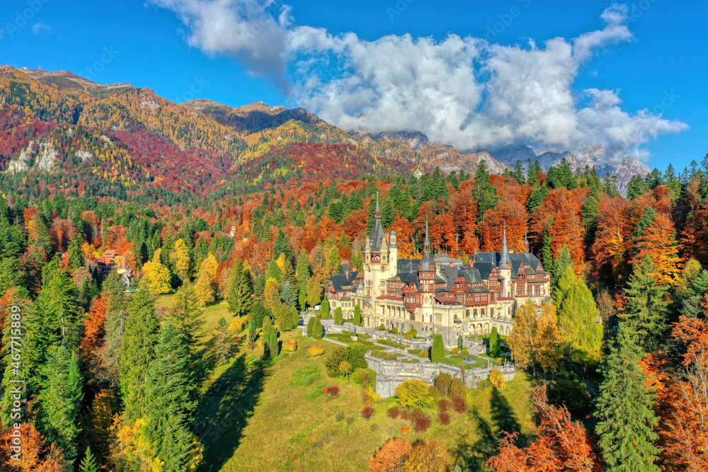Peles Castle, Sinaia, Prahova County, Romania: Drone view of famous Neo-Renaissance castle in autumn colours, at the base of the Carpathian Mountains, Europe - obrazy, fototapety, plakaty 