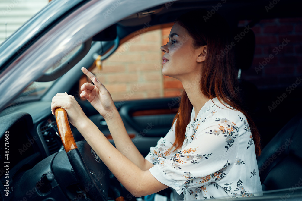 cheerful woman driving a car looks out of the window