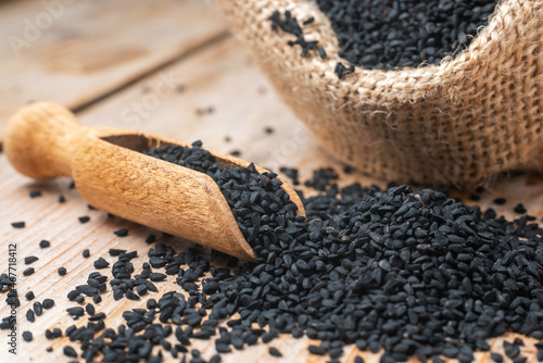 Black cumin seeds and wooden scoop, texture background