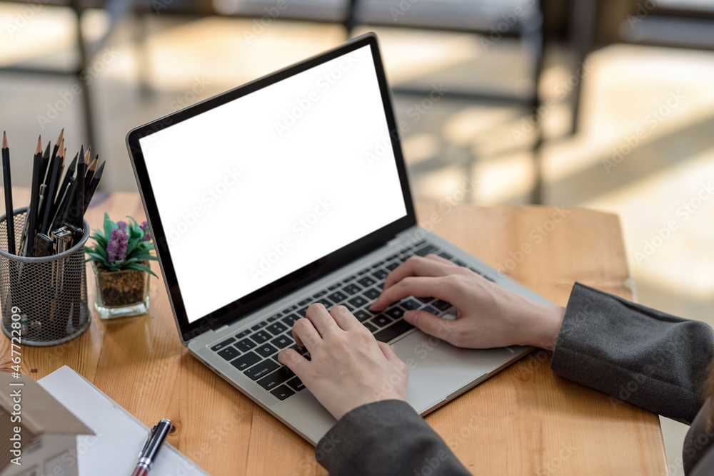 Close-up of a businesswoman working on a laptop blank white screen at office. Mock up. Close-up of a businesswoman working on a laptop blank white screen at office. Mock up.