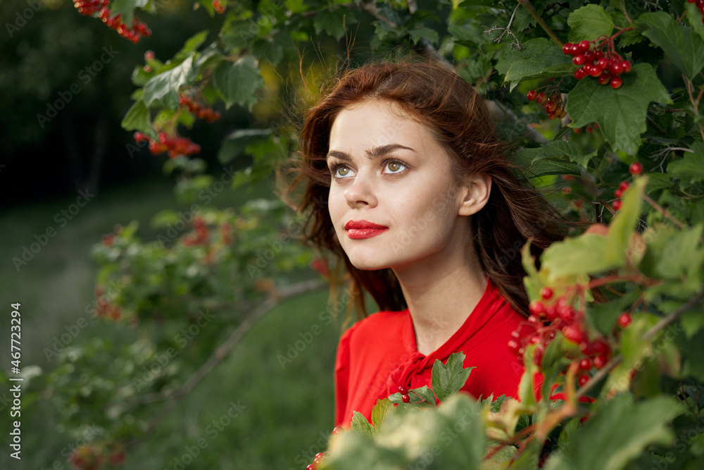 Naklejka premium cheerful woman in a red shirt bush berries countryside