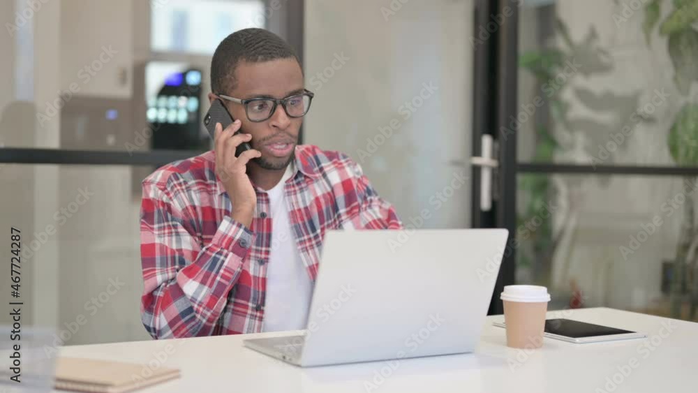 African Man Talking on Smartphone while using Laptop African Man Talking on Smartphone while using Laptop