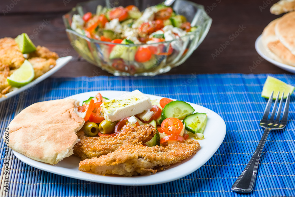 Baked fish served with vegetable salad with feta cheese